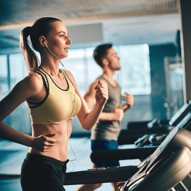 Fit man and woman doing cardio training on treadmills in a modern fitness centre