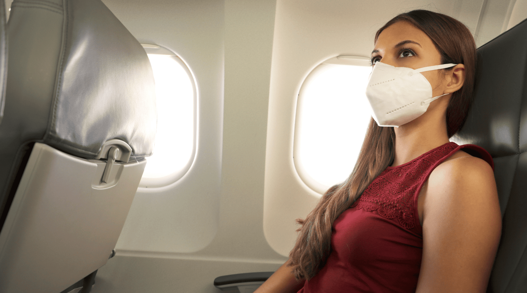 Woman wearing a face mask while seated on an airplane
