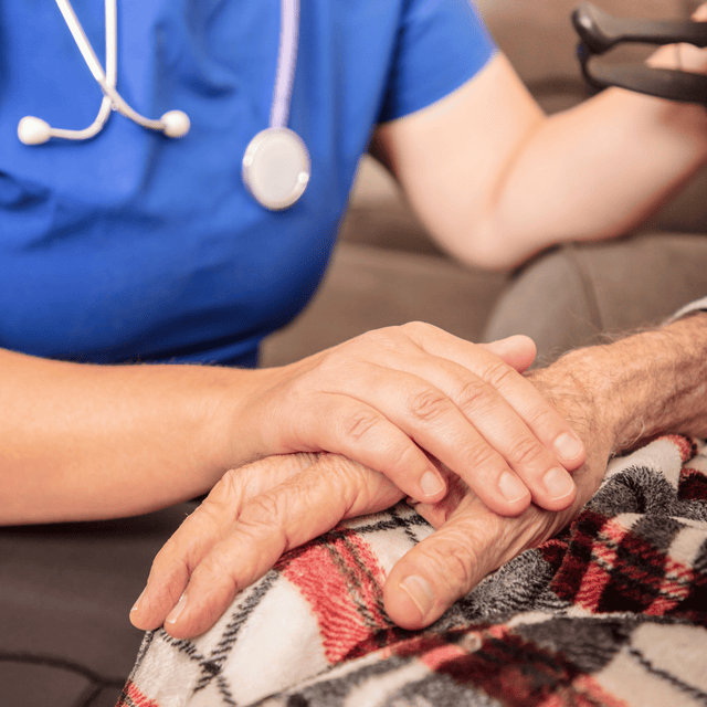 Healthcare worker providing comfort to an aged patient at home