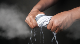 Man twisting wet towel to be used as face mask