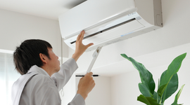 Man servicing air conditioner unit at home