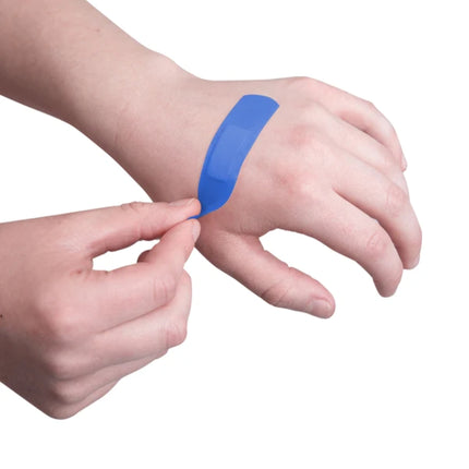 A close-up of a person's hand and wrist with a blue athletic tape bandage being peeled off, set against a plain white background.
