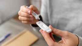 Woman dropping sample on COVID test kit